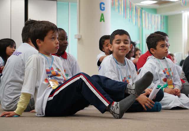 Kids sit together on floor in classroom