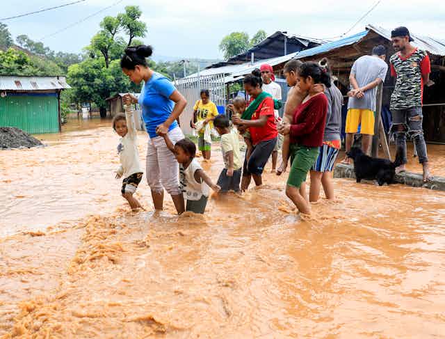 Dili residents wade through floodwaters