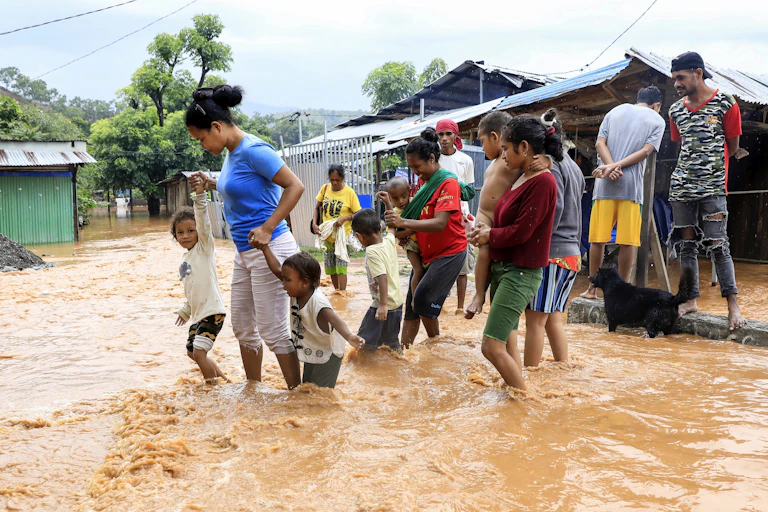 Dili residents wade through floodwaters