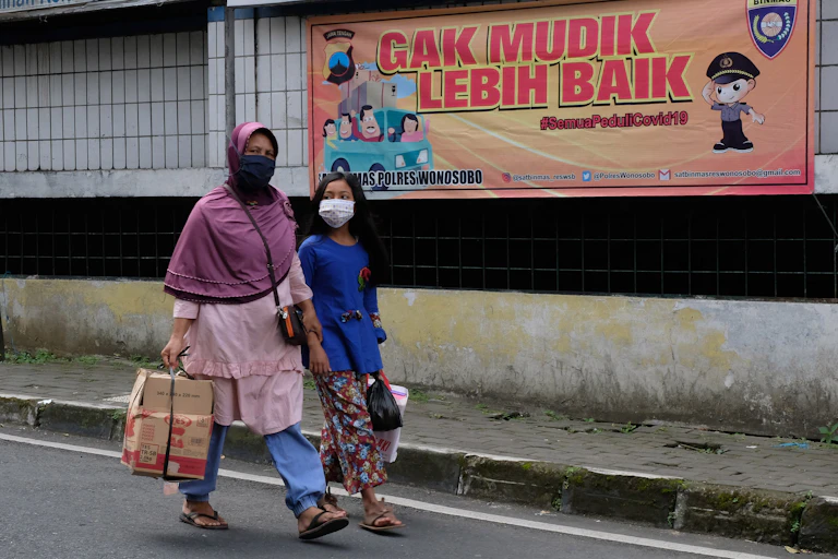 Warga berjalan di samping spanduk larangan mudik di kompleks pasar Induk Wonosobo, Jawa Tengah.