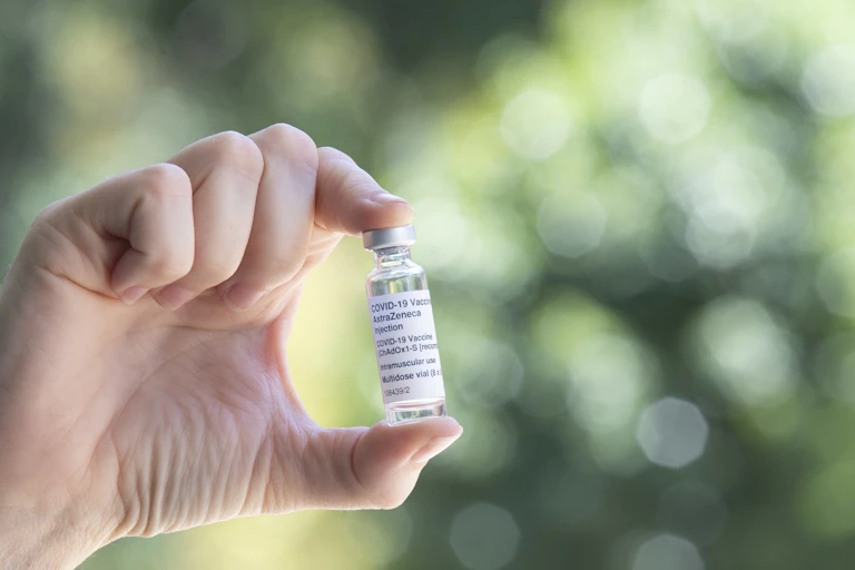 Hand holding a vial of the AstraZeneca vaccine.