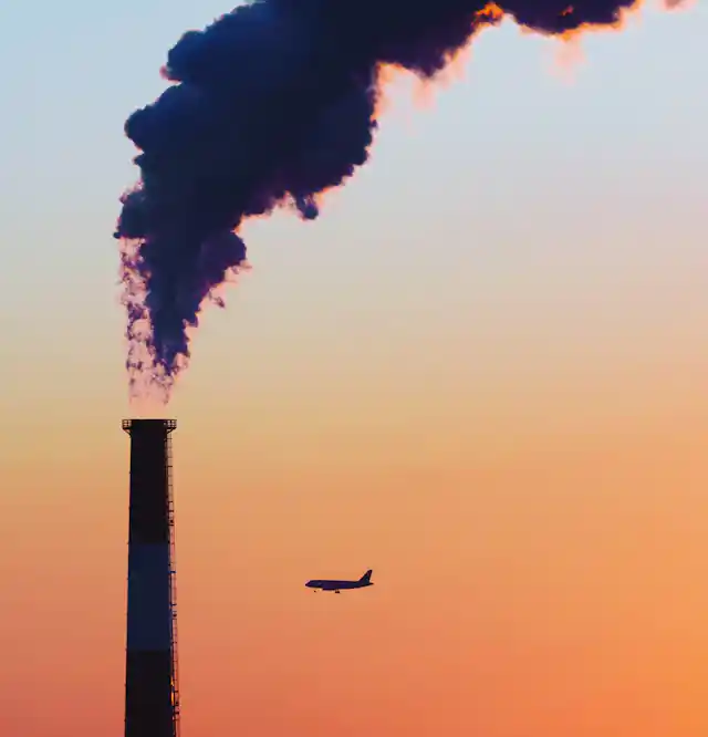 Smoke rises from a chimney against a sunset sky.