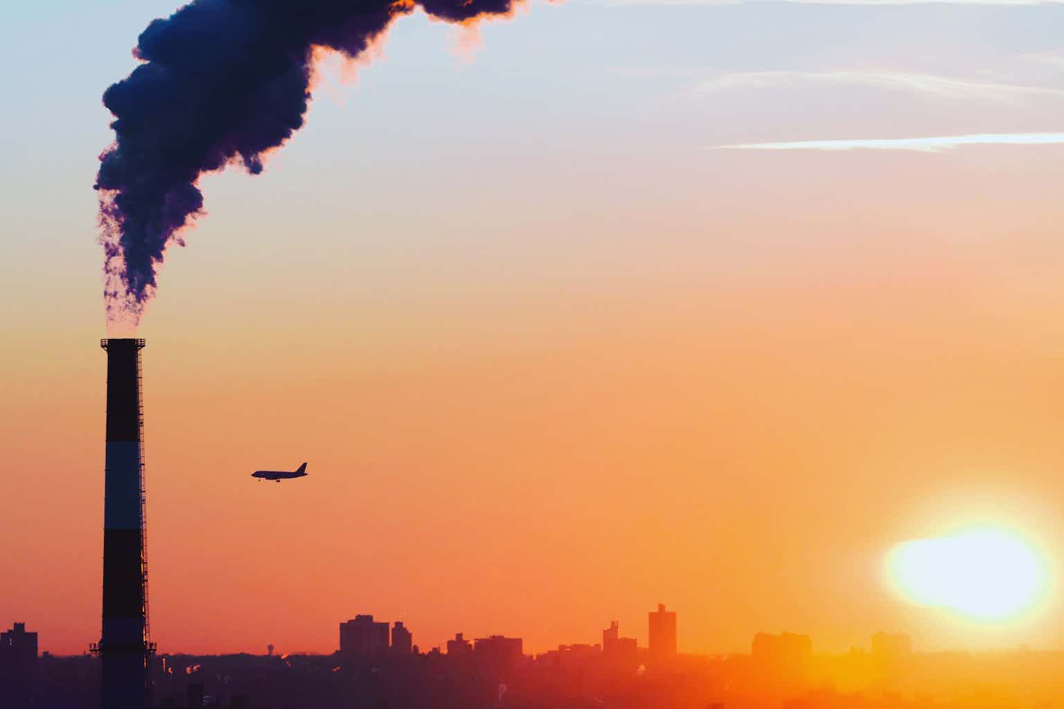 Smoke rises from a chimney against a sunset sky.