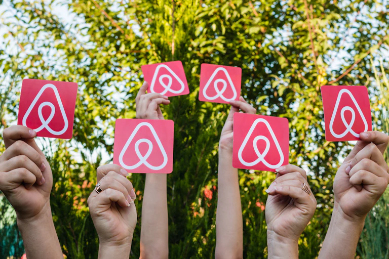 Six hands holding up Airbnb logos