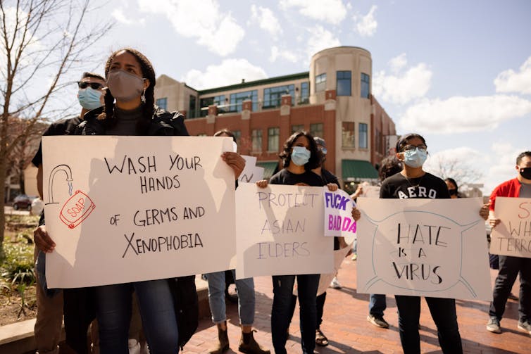 A group of mask-wearing protestors hold signs in the middle of the street.