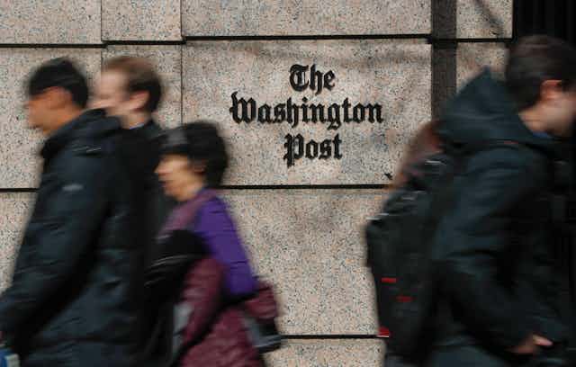 People walk in front of the Washington Post buidling