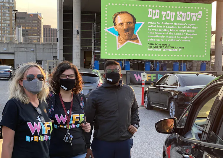 Four people standing in masks outdoors.