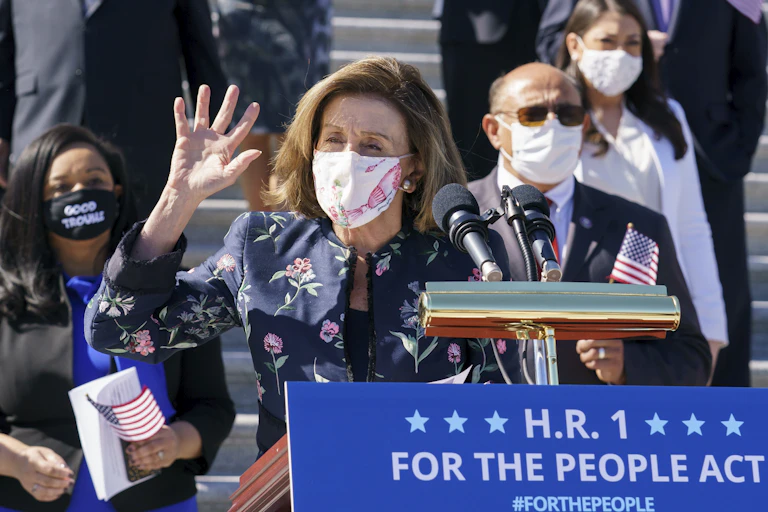 Nancy Pelosi talking to reporters behind a lectern in front of the Capitol. a