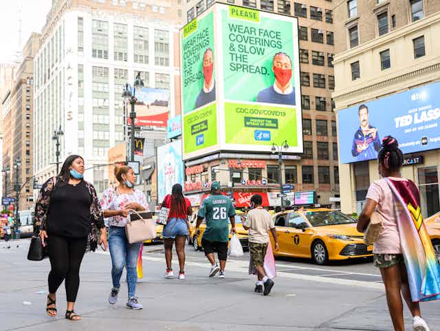 pedestrians walk in foreground of CDC billboard