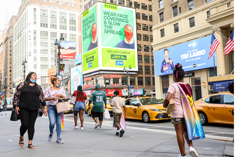 pedestrians walk in foreground of CDC billboard