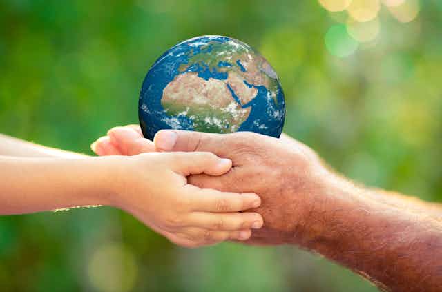 Man and child's hands holding Earth