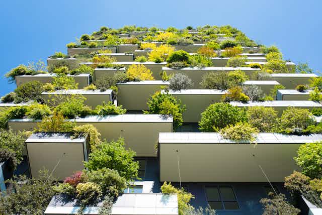 Modern and ecologic skyscrapers with many trees on balcony.