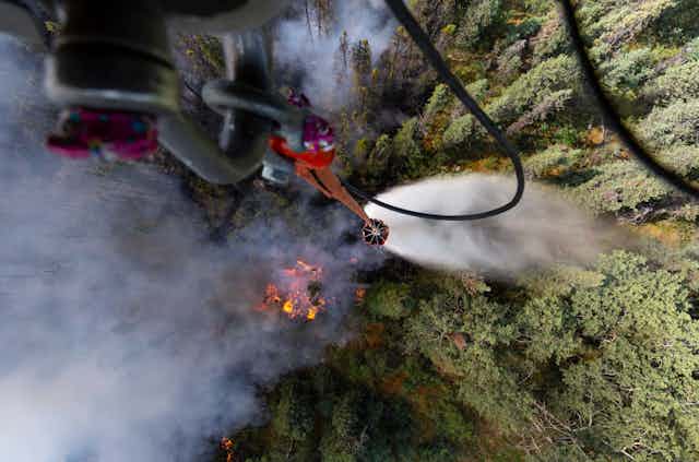 View of a forest fire looking straight down from a military helicopter dropping water.