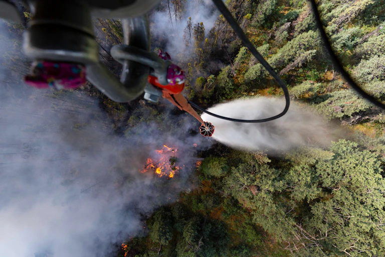 View of a forest fire looking straight down from a military helicopter dropping water.