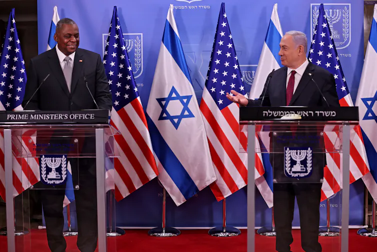 US defense secretary Lloyd Austin, left, and Israeli prime minister Benjamin Netanyahu standing a lecterns on a stage in front of the US and Israeli flags.