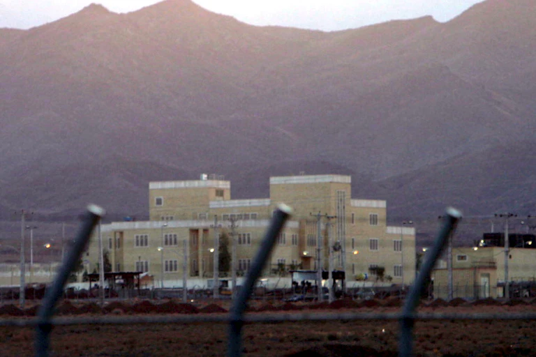 Large building behind security fence with mountains in background