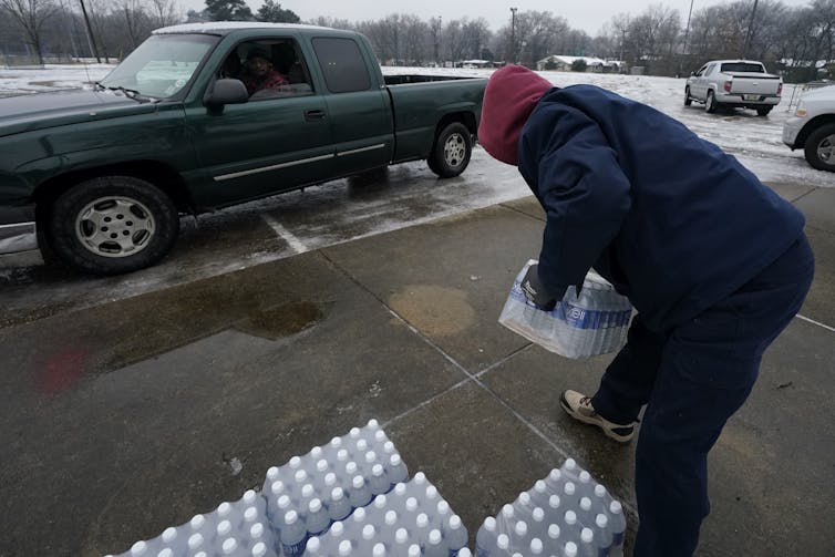 A city worker loads bottled water into a pickup truck.