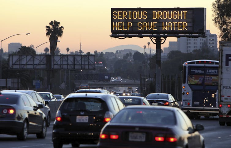 Cars drive on the Hollywood freeway during the morning commute as an electronic sign warns: 'Serious drought. Help save water.'