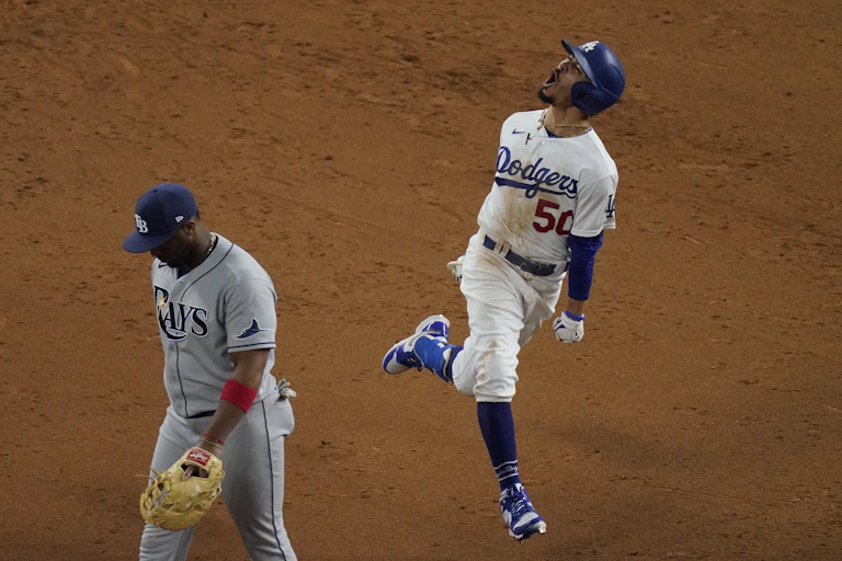 Los Angeles Dodgers player Mookie Betts shows jubilation after hitting a home run in the 2020 World Series while a member of the Tampa Bay Rays looks dejected while