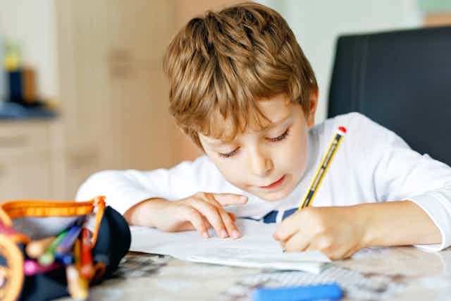 Young boy doing schoolwork at desk.