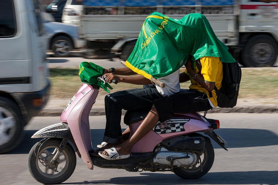 Supporters of ruling party Chama Cha Mapinduzi (CCM - Party of the Revolution) drive with the party's flag on their heads on a motorcycle.
