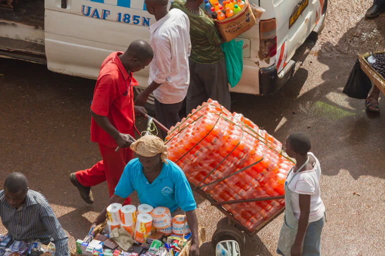 A man moving cases of soda pop on a trolley in the street
