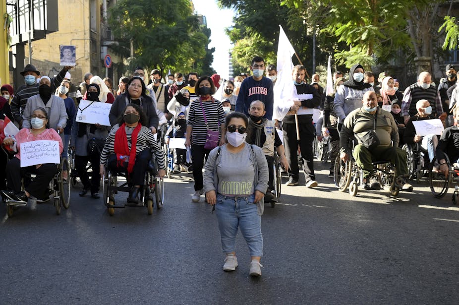Group of disabled protesters with face masks and signs walking down a road in Beirut