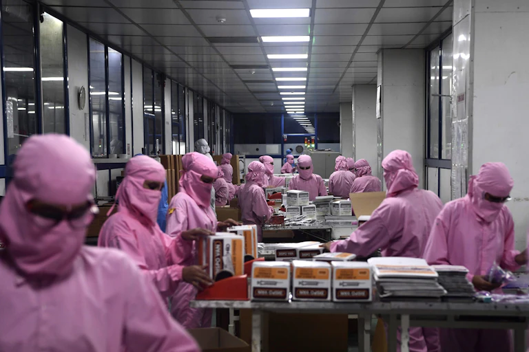 People wearing pink protective clothing and masks handle boxes on a table