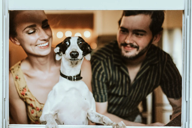 Man and a woman in the window with their dog.
