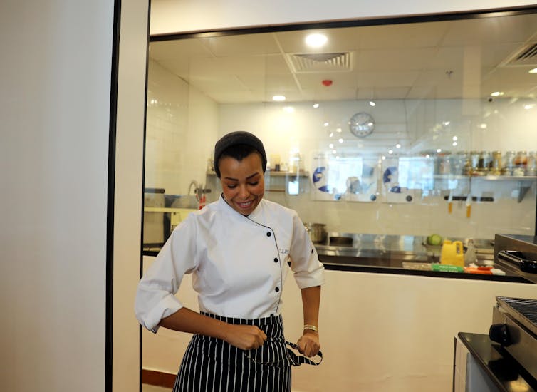 Woman wearing chef's whites in restaurant kitchen.
