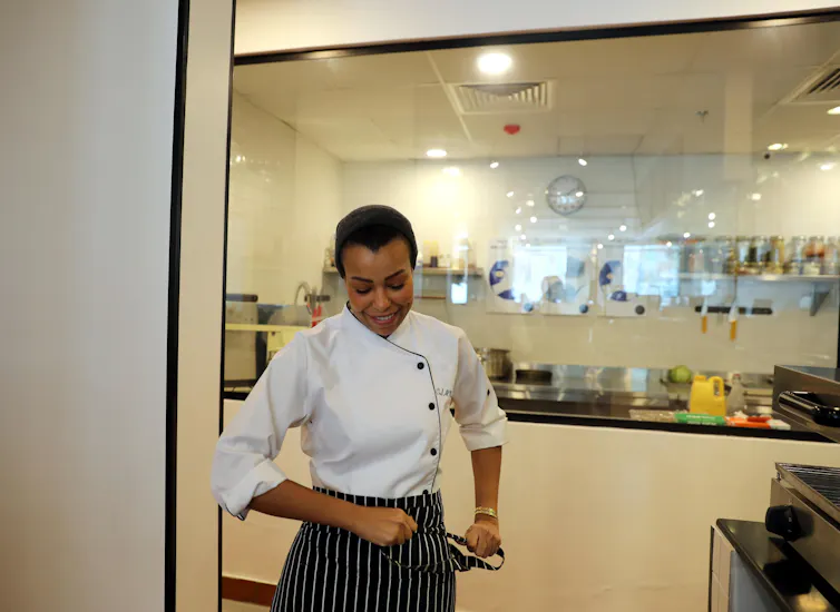 Woman wearing chef's whites in restaurant kitchen.