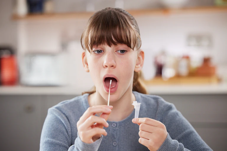 A girl using a rapid (lateral flow) coronavirus test at home