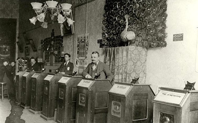 Men standing at Kinetoscopes.