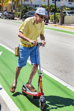 Older man on a scooter in a bike lane