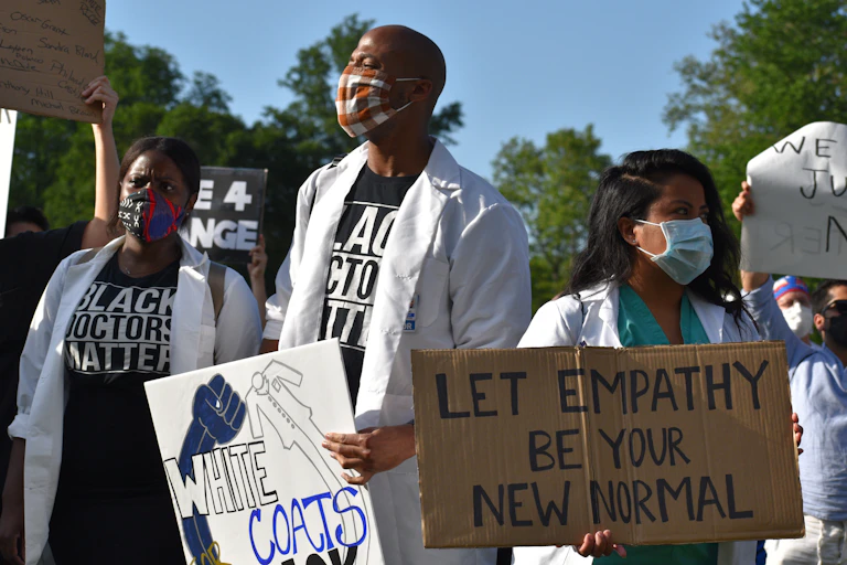 Health care workers wearing white coats protest racist health care.