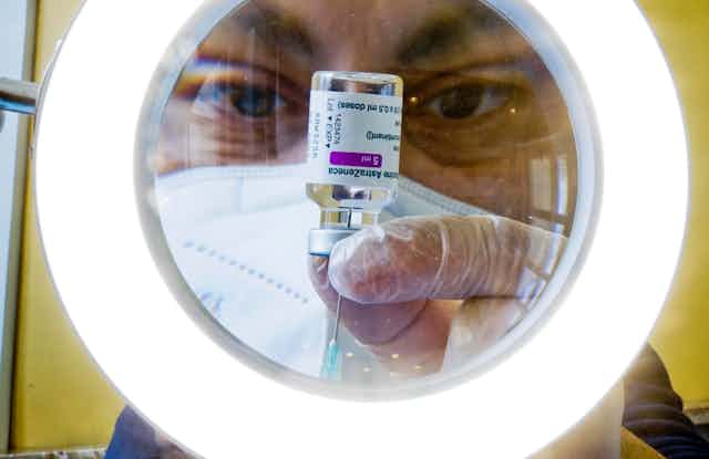 A man extracting AstraZeneca vaccine from a vial