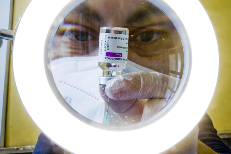 A man extracting AstraZeneca vaccine from a vial