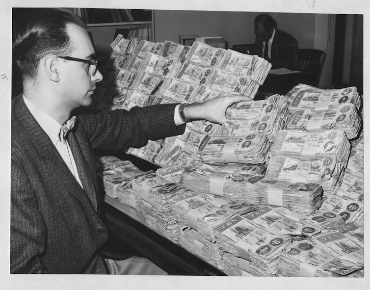 A man in glasses looks at stacks of Confederate currency