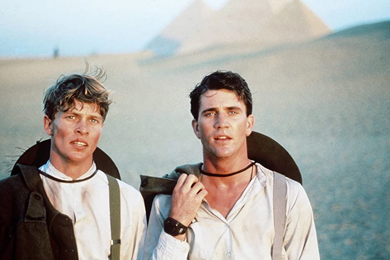 Two young men stand in front of pyramids
