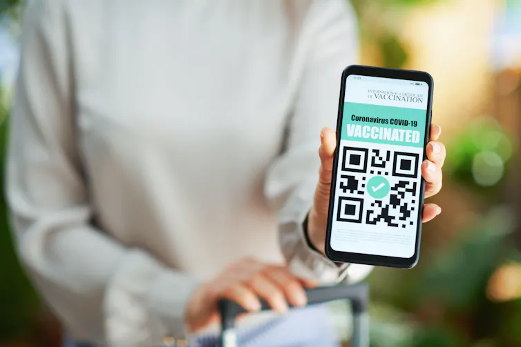 A person holding up a mobile phone showing a vaccine certificate.
