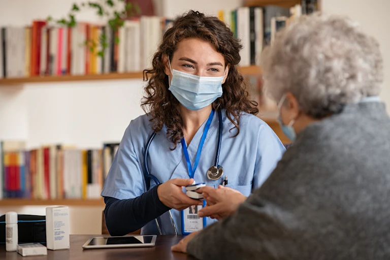 A doctor checks an elderly ladies blood-oxygen levels.