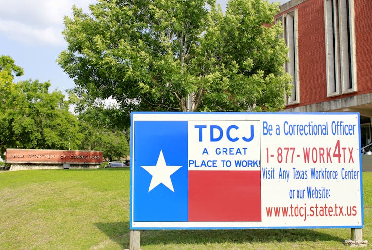 Photo of the TDCJ headquarters with a sign outside painted like the flag of Texas