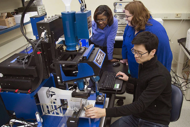 Researchers working in a lab studying effect of heat on hair with infrared microscope.