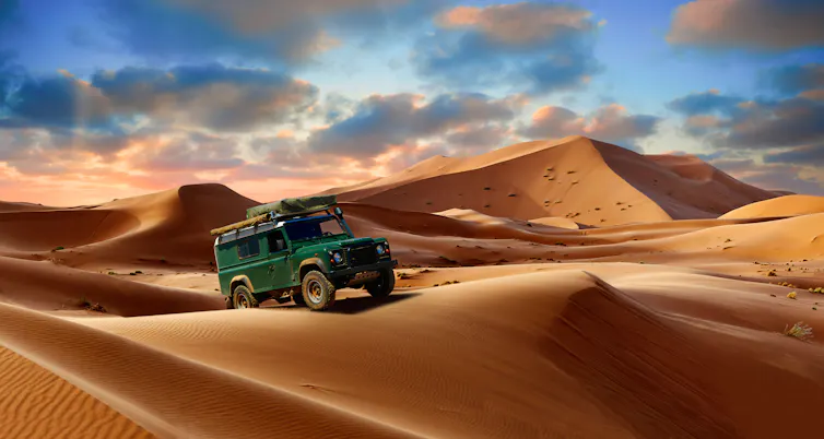 A green land rover on desert dunes