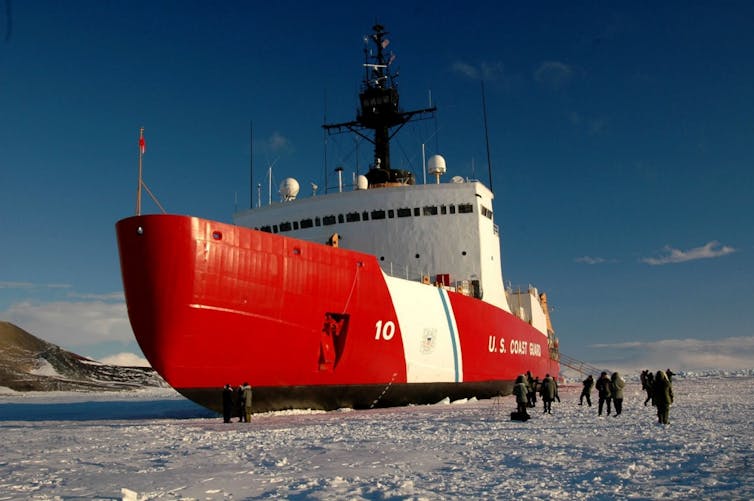 People walk on the ice beside the giant icebreaker