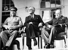 The three leaders sitting in chairs on a portico