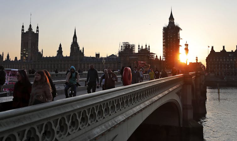 People walking across Westminster Bridge, London, during sunset