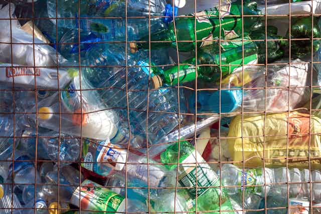 Plastic bottles are piled up behind metal fencing