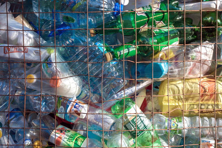 Plastic bottles are piled up behind metal fencing