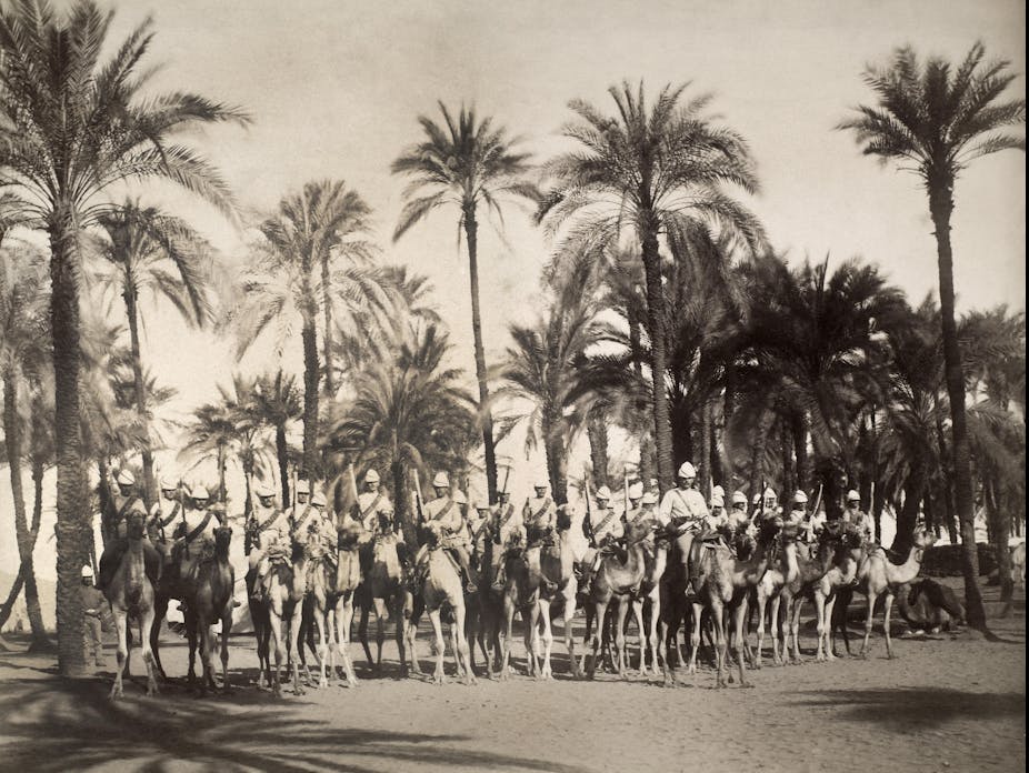 Black and white photo of British soldiers mounted on horses with palm trees in the background